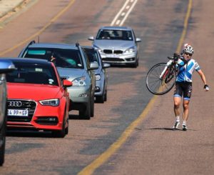 Rider pictured carrying his bike beside some traffic congestion in stage one of the Panorama Tour. Photo: HH Photography & Design