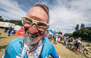 A rider bites his medal after finishing day three of sani2c Adventure