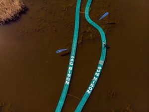 An aerial view of riders crossing a bridge over water on day one of sani2c Trail