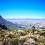A rider ascending a climb with a spectacular backdrop view during stage one of The U MTB Stage Race. Photo: Chris Hitchcock