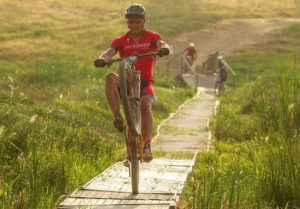 A rider performing a wheelie on a suspension bridge during stage three of the Wines2Whales Chardonnay. Photo: Greg Beadle