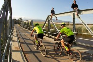 Riders moving over a bridge with some spectators in stage three of the Wines2Whales Chardonnay. Photo: Greg Beadle