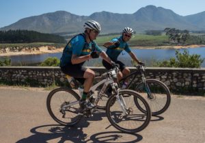 Riders moving along a road with a fine view of a lake and mountain range in stage three of the Wines2Whales Chardonnay. Photo: Greg Beadle