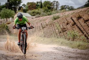 A rider crashing and splashing through a puddle during the TransCape MTB Encounter. Photo: Jacques Marais