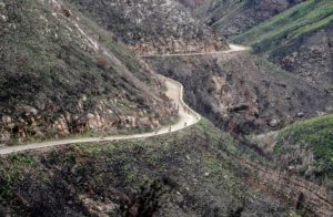 A wide, aerial shot of riders taking on a bend on the edge of a mountain-side during the TransCape MTB Encounter. Photo: Jacques Marais